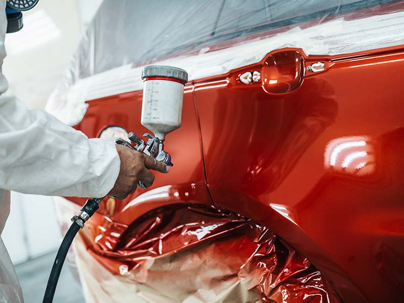Techniciens qui applique une couche de peinture automobile sur une portière au garage drevet Techniciens qui applique une couche de peinture automobile sur une portière au garage drevet